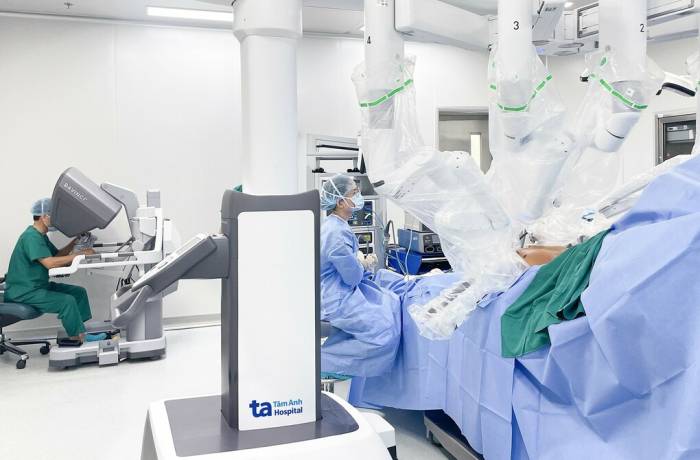 Phó giáo sư Vĩnh (bên trái) điều khiển robot phẫu thuật cắt khối u trong lồng ngực cho người bệnh. Ảnh: Bệnh viện Đa khoa Tâm Anh