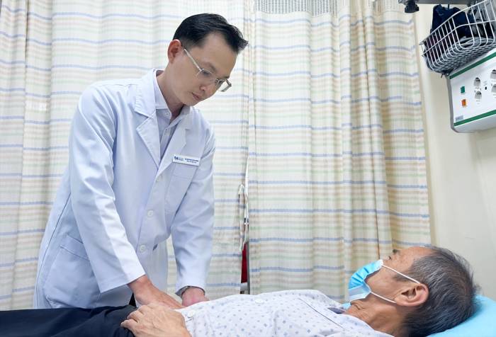 Bác sĩ Trọng khám vùng bụng cho ông Thuận. Ảnh: Bệnh viện cung cấp