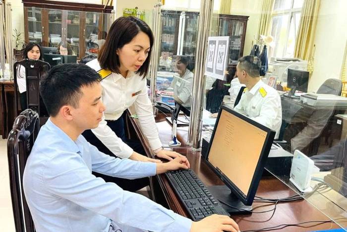 Cán bộ thuế hướng dẫn người dân thực hiện thủ tục. Ảnh: Cục Thuế
