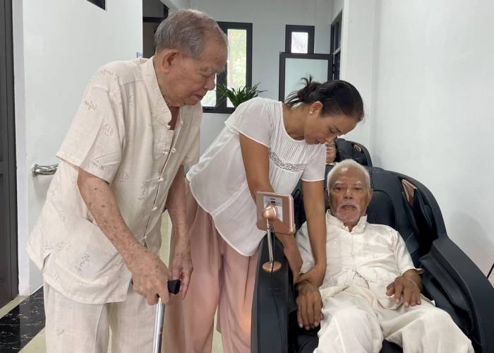 Chị Mai Hương hỗ trợ bố nằm máy massage tại Cơ sở chăm sóc người cao tuổi phường Tây Hồ, hôm 1/10. Ảnh: Phan Dương