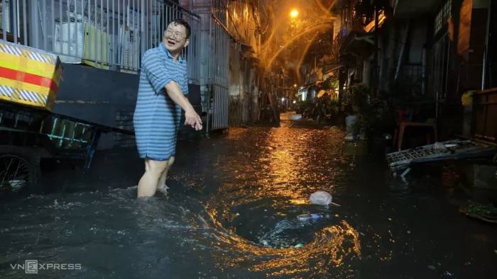 Một số người dân ở trong hẻm đường Chu Văn An mang sọt đi thu gom rác bị cuốn theo xoáy nước làm tắc miệng cống, tháng 9/2029. Ảnh: Đình Văn
