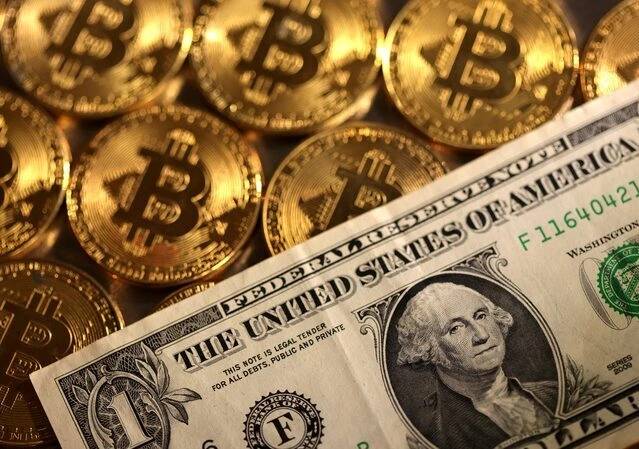 Tờ 1 USD được đặt trên các đồng xu biểu trưng của Bitcoin. Ảnh: Reuters