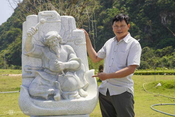 Nghệ nhân điêu khắc Nguyễn Văn Nho bên tác phẩm Đá nở hoa, phác họa tổ nghề làng đá Non Nước. Ảnh: Nguyễn Đông